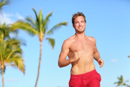 Man jogging on a beach, symbolizing vitality and wellness.
